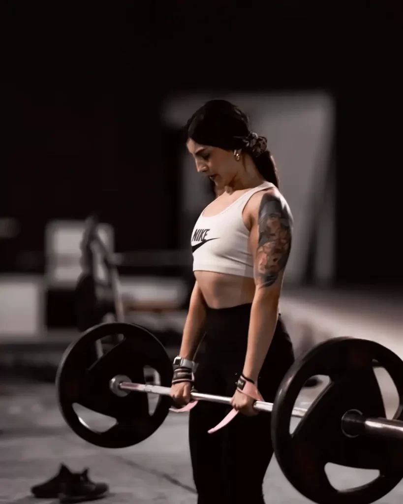 Mujer con tatuajes preparando ejercicio de peso muerto con barra en gimnasio JaleaFit San Felipe